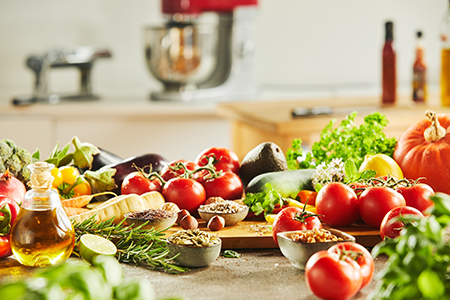 Side view of assorted vegetables including tomatoes and pumpkins covering cutting board in front of 