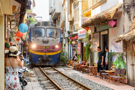 Train passing narrow road in old town in Hanoi, Vietnam.