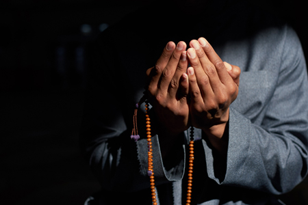 Close up of a Muslim mans hands praying and holding prayer beads