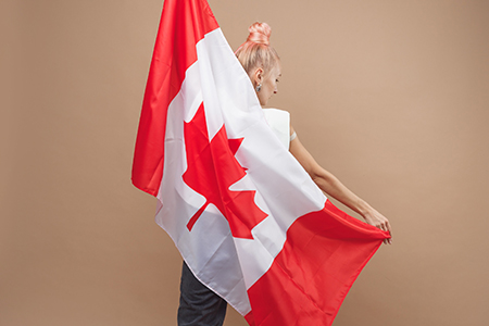 Beautiful asian woman, a sports fan, standing in front of a Canadian flag