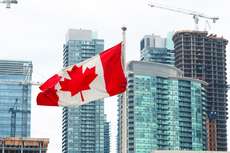 The Canadian flag waving on the background of skyscrapers under construction