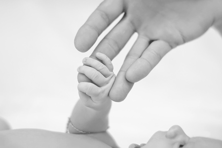 Newborn baby with mother's hand. Black and white photo.