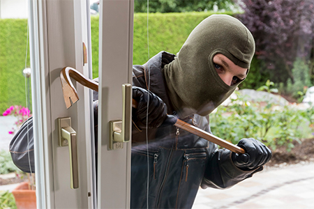 burglar at a window trying to break into house