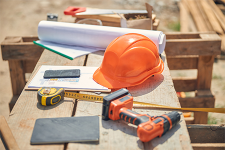 Orange protective helmet and builder instruments outside