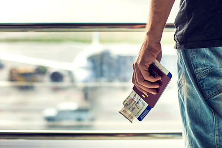 Closeup of man holding passports and boarding pass at airport