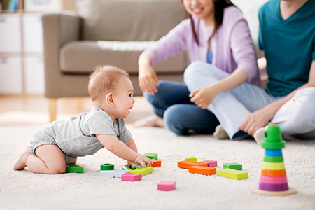 happy mother, father and baby boy playing toy blocks at home