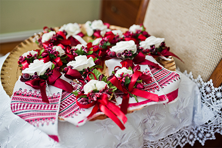 Bunch of beautiful wedding boutonnieres tied with ribbons laying on the golden tray