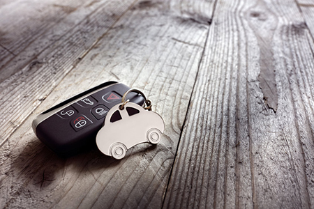 Car shape keyring and keyless entry remote on wood background