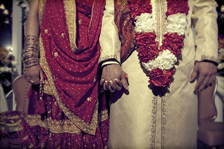 Pakistani wedding couple holding hands.