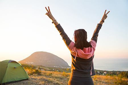 A girl in the mountains, rejoices in the sun. Panoramic view of the mountain and the sea from above.