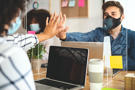 Young people in co-working creative space wearing surgical mask protection and keeping social distan