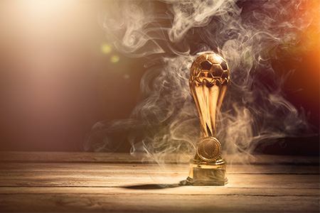 soccer sports trophy cup on wood desk with dramatic strong contrast light