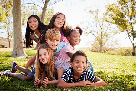 Multi-ethnic group of kids lying on each other in a park