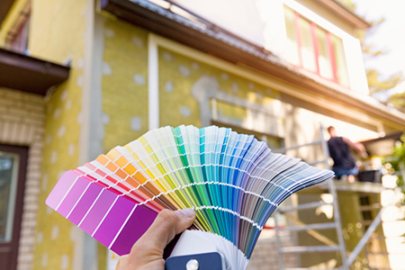 paint colour palettes held up in front of house