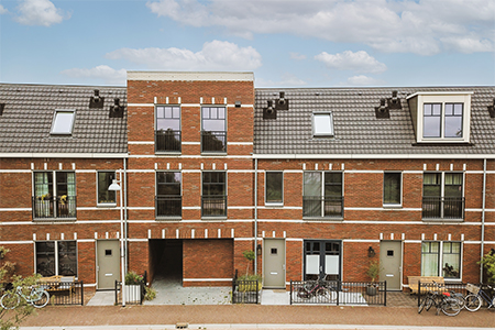 Panorama view of brick houses from an empty sidewalk street with bicycles