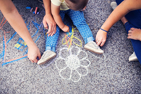 parents and baby drawing with chalk on ground