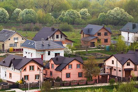 Street with new modern comfortable brick cottages with yards and blooming gardens on background