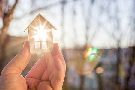 person holding small house-shaped block