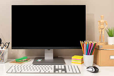 Workspace showing computer with black blank screen, keyboard, mouse and various stationery items
