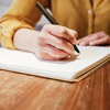 unrecognizable young caucasian woman writing on notebook at a cafe