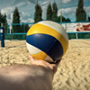 Volleyball ball in the hand of a man on the beach