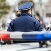 Security service officer cop with traffic baton guarding street near police car with siren light