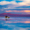 Car standing in middle of salt flat reflecting blue sky, Salar de Uyuni, Bolivia