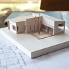 An architecture model with shop drawing paper and laptop on table in office with blur nature backgro