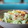 Caesar salad with crispy bread and bacon close up on wood background