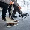 Couple sitting on bench at the ice rink, putting on ice skates