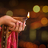 Close up Indian woman in traditional sari lighting oil lamp and celebrating Diwali or deepavali, fes