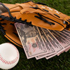 dollar banknotes in baseball glove near ball on green grass, concept