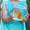 Little baby girl holding a fishbowl with a goldfish