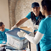 man volunteering at donation center and passing box with clothes to his coworker