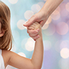 People, charity, family and adoption concept - close up of woman and little girl holding hands over 