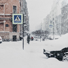 Outdoor shot of beautiful snowy city with transport and people, covered with thick white snow