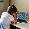 Boy student having a video call with his classmates in elementary school during covid-19 school shut