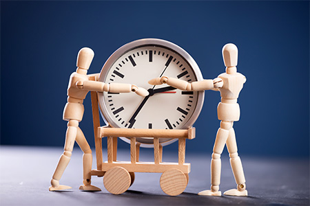 Two wooden figure holding a clock - concept