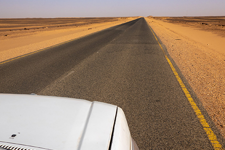 Straight as a die, gray asphalt road through the desert of Sudan-