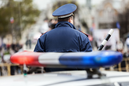 Security service officer cop with traffic baton guarding street near police car with siren light