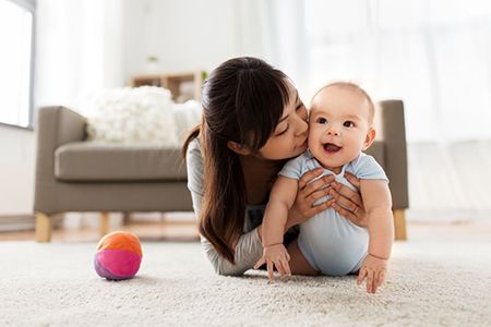 happy young mother kissing little baby at home