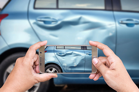 Close up hand of woman holding smartphone and take photo of car accident