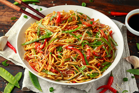 Chow mein, noodles and vegetables dish with wooden chopsticks