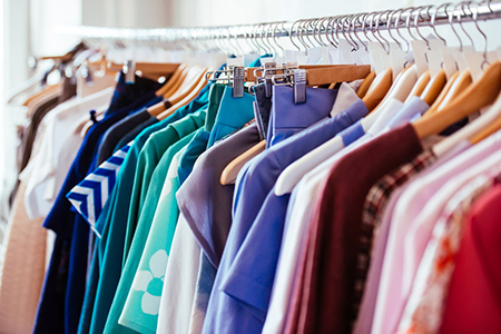 Colorful women's dresses on hangers in a retail shop. Fashion and shopping concept