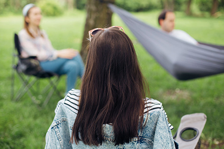 Social distancing. Small group of people enjoying conversation at picnic with social distance in sum