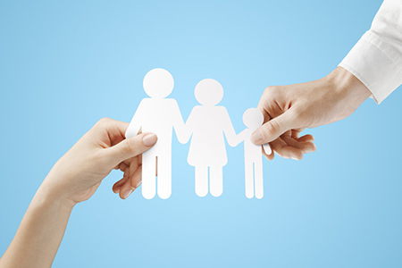 hands holding paper family on a blue background