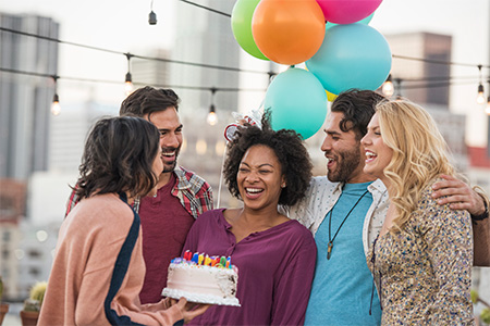 Friends celebrating birthday party on rooftop with birthday cake