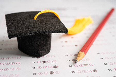 Graduation hat and pencil on answer sheet background