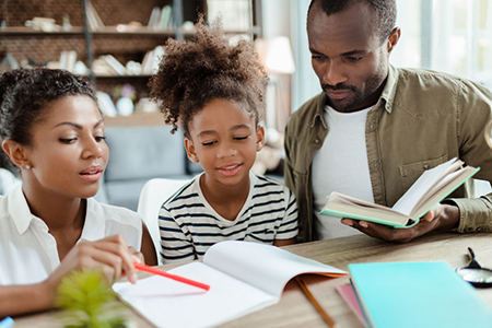 Mom and dad helping daughter with homework