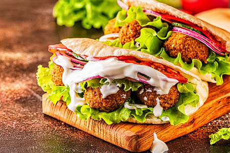 Falafel and fresh vegetables in pita bread on dark background.